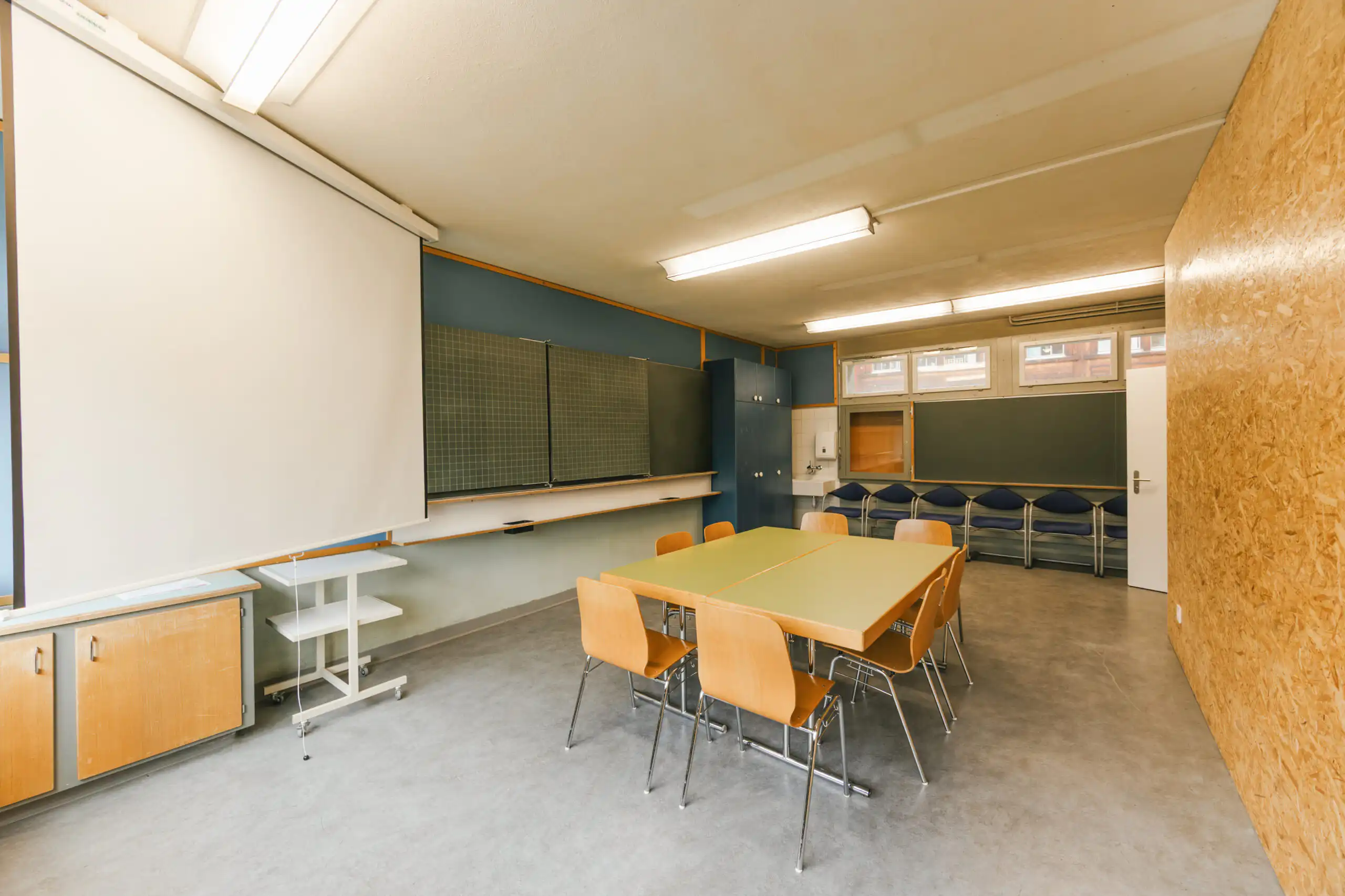 Diemtighuus_Räume-3 Moderner Seminarraum mit Tischen, Stühlen, Projektor und Tafeln für Workshops und Meetings.