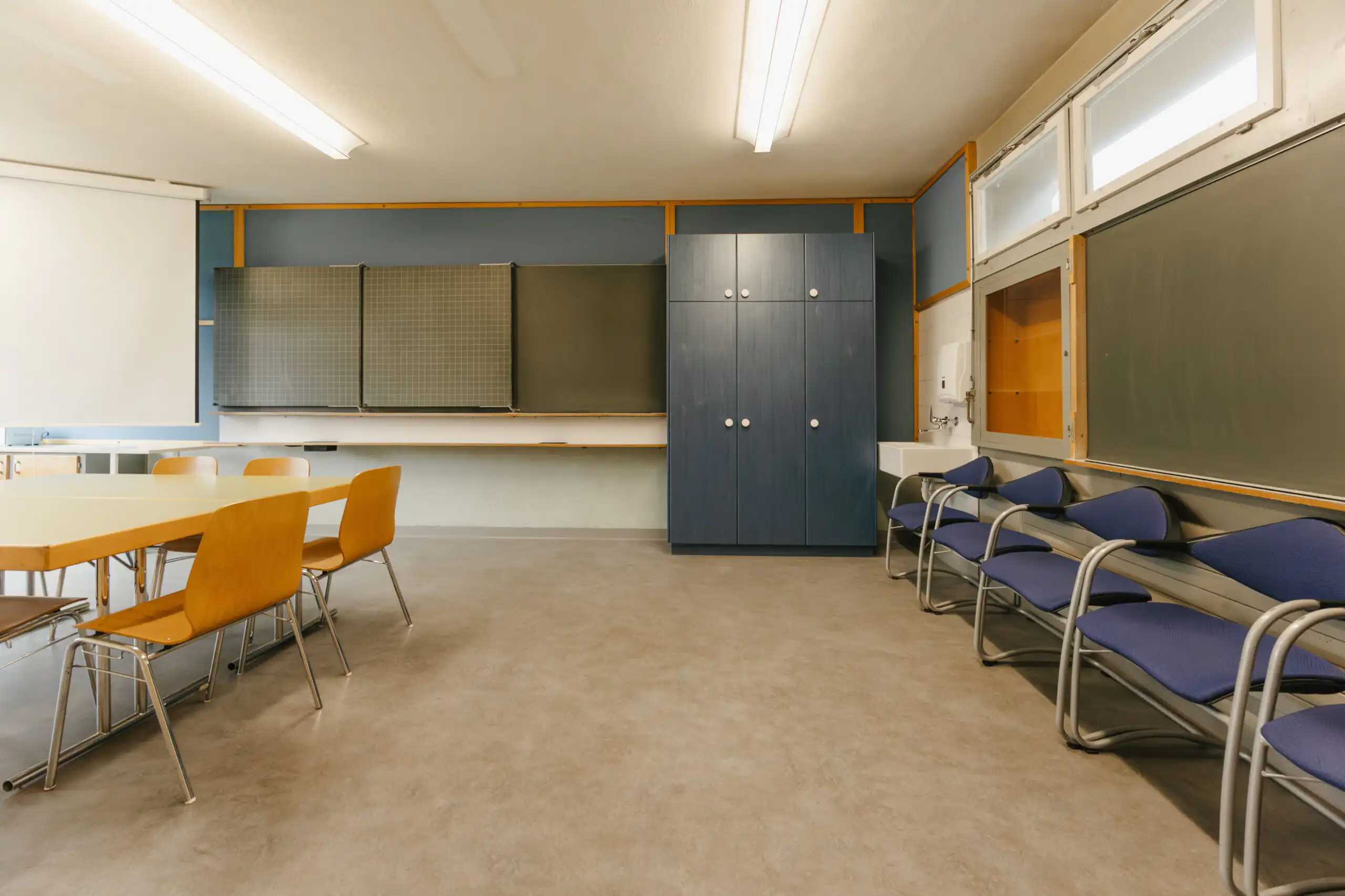 Diemtighuus_Räume-8 Moderner Seminarraum mit Holztisch, Stühlen, blauer Schrankwand und Tafel, ideal für Meetings oder Workshops.
